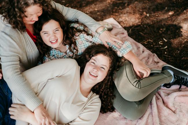 20180520-DSC_5298 Daughter laying in the lap of her younger sister and mother during a family photography session at Hyde Park, Perth