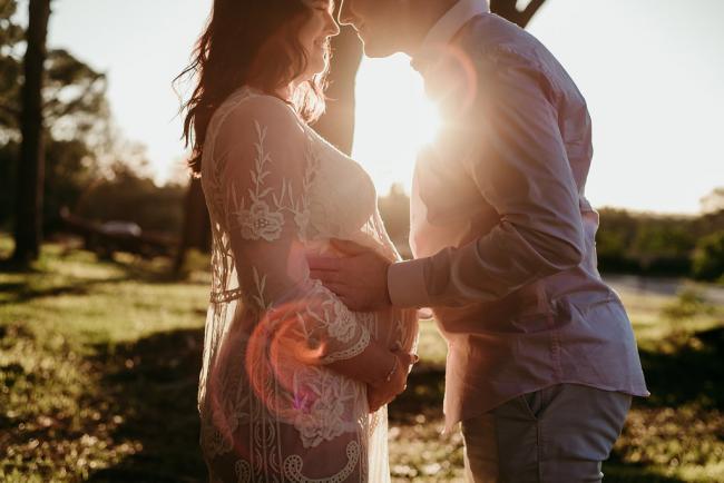 20180614-DSC_9179 Man holding his pregnant partner's tummy during a golden hour maternity photography session at The Pines Wanneroo in Perth