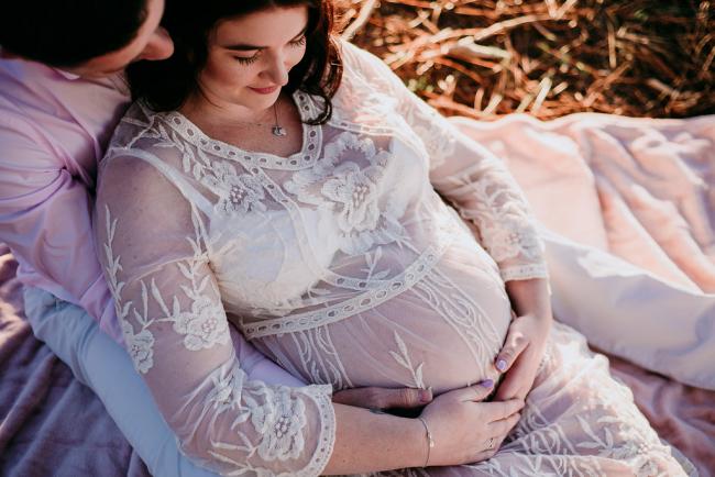 20180614-DSC_9322 A pregnant woman leaning back on her partner as they both look down during a maternity photography session at The Pines Wanneroo in Perth
