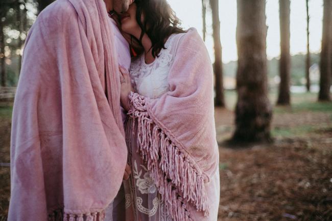 20180614-DSC_9762 Close up of a woman leaning into her partner with a blanket wrapped around them during a golden hour maternity photography session at The Pines Wanneroo in Perth