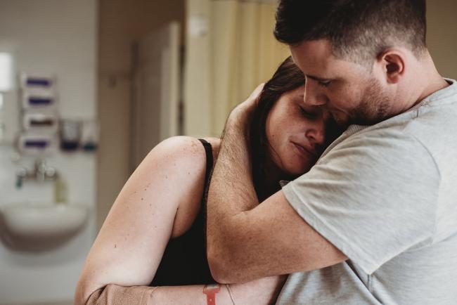 Man hugging his partner's head as she is in labour during a Perth birth photography session