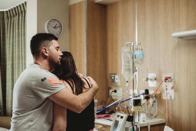 Man wrapping his arm around his labouring partner's shoulders during a Perth birth photography session