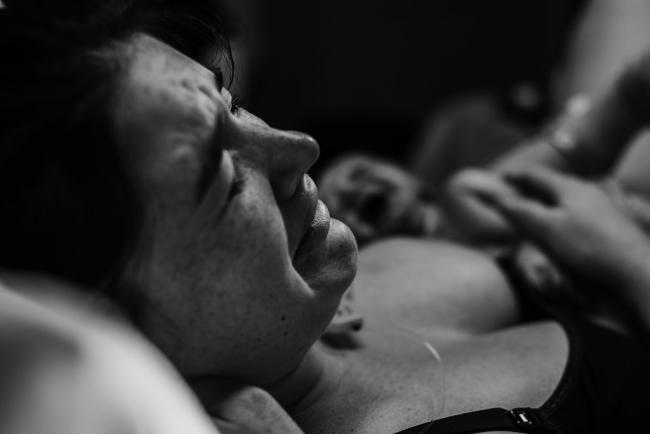 Black and white image of a mother crying after meeting her new baby for the first time during a Perth birth photography session