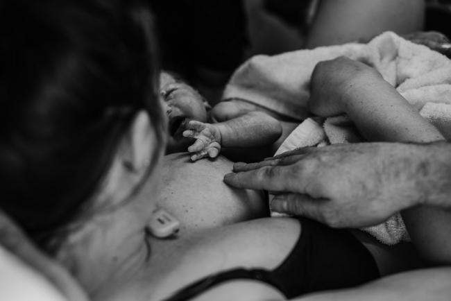 Black and white image of the start of a first breastfeed with their new baby during a Perth birth photography session