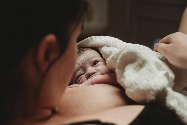 New baby looking up at her mother during a Perth birth photography session