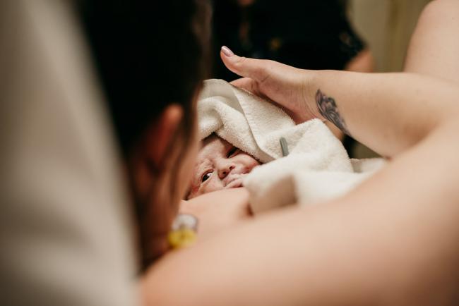 New baby looking up at her mother during a Perth birth photography session