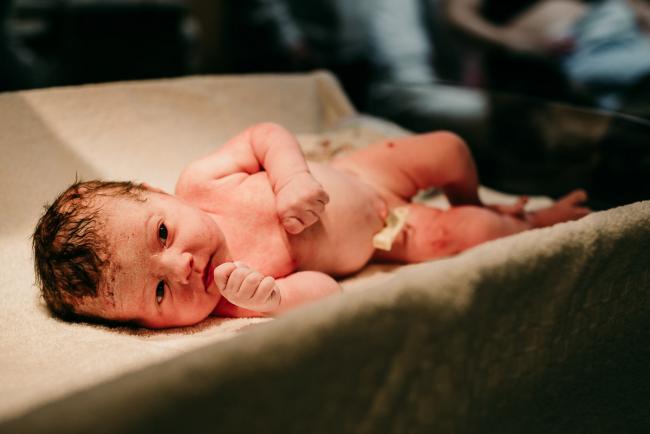 New baby laying naked and being weighed and measured during a Perth birth photography session