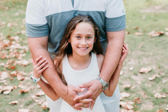 Daughter embraced by fathers arms during family photography Perth session