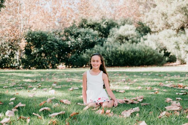 Girl sits on grass during family photography Perth session