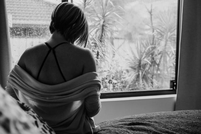 Back of pregnant woman sitting on her bed during in-home maternity photography Perth session