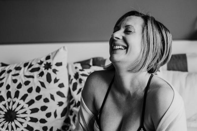 Black and white image of woman laughing during in-home maternity photography Perth session
