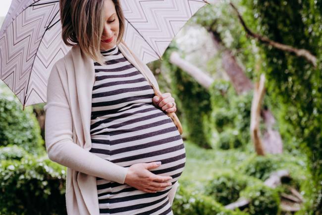 Pregnant woman holding her tummy during maternity photography Perth session at The Secret Garden