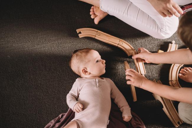 20180610-20180610-DSC_8062 new baby playing on the ground surrounded by toy train tracks during lifestyle newborn photography Perth session