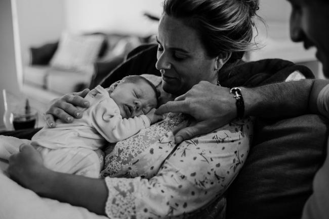 20180615-DSC_0103 Black and white image of woman holding her new baby and father touching baby's hand during lifestyle newborn photography Perth session