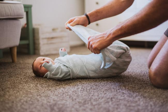 20180615-DSC_0730 Father wrapping new baby on the floor during lifestyle newborn photography Perth session