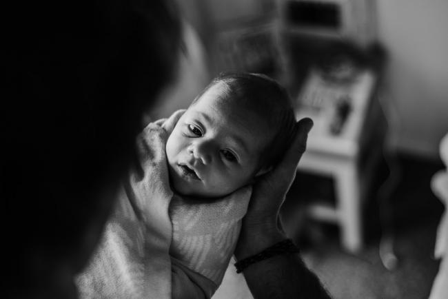 20180615-DSC_0824 Black and white image of baby's face in dad's hands during lifestyle newborn photography Perth session