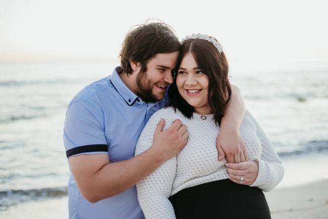 20180616-20180616-DSC_1608 Man with arms wrapped over partners shoulders during maternity photography Perth session at Burns Beach