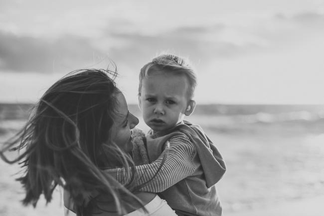 20180703-DSC_5695 black and white image of little boy frowning as he's being held by his mother during a maternity photography Perth session at Burns Beach