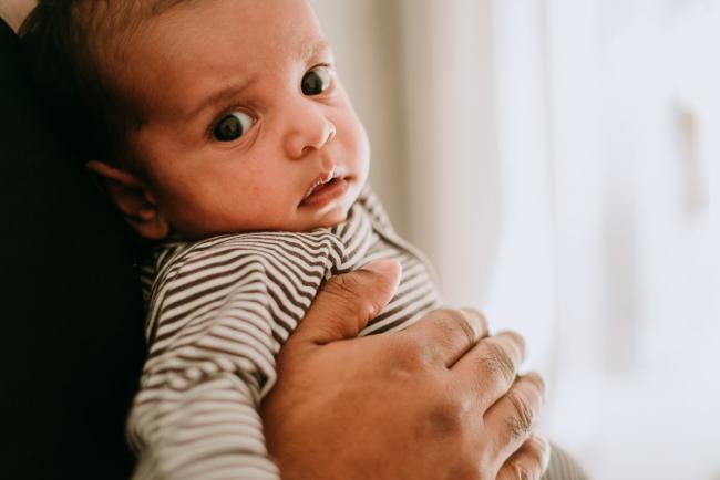 20180706-20180706-DSC_6376 New baby looking at the camera as being held by father during lifestyle newborn photography Perth session