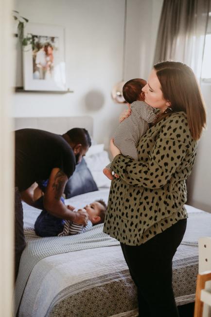 20180706-20180706-DSC_6441 mother holding new baby while father wrestles with son on the bed during lifestyle newborn photography Perth session