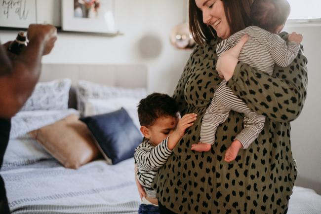 20180706-20180706-DSC_6452 mother holds new baby as son hugs her legs during lifestyle newborn photography Perth session