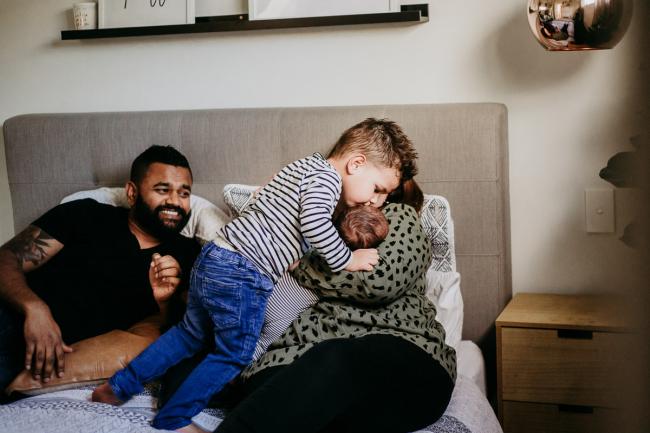20180706-20180706-DSC_6510 Brother kissing his new baby brother who is being held by mother during lifestyle newborn photography Perth session
