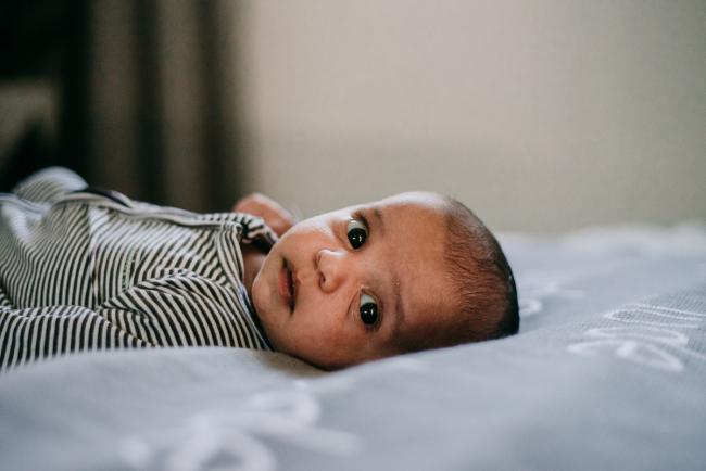 20180706-20180706-DSC_6713 Baby laying on bed and looking at camera during lifestyle newborn photography Perth session