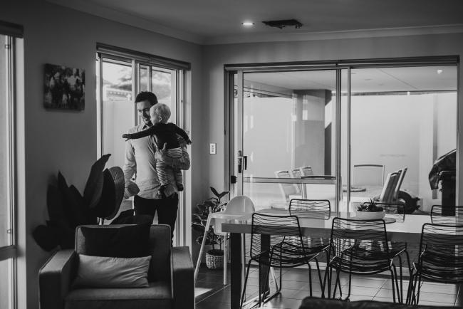 20180708-DSC_7808 black and white image of father holding his son by the door in the living room during an in-home family photography Perth session