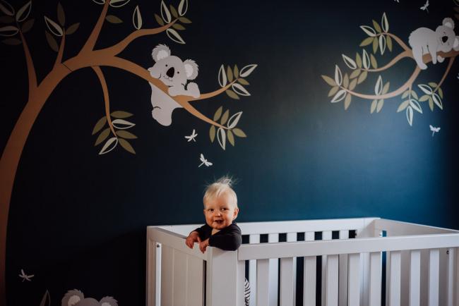 20180708-DSC_8060 little boy standing in his cot in front of a koala mural during an in-home family photography Perth session