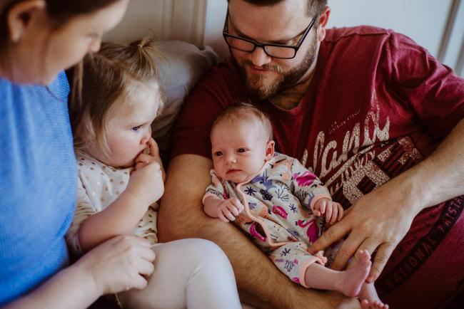 20180720-DSC_9192 Family of 4 sitting on the bed with little girl picking her nose during lifestyle newborn photography Perth session
