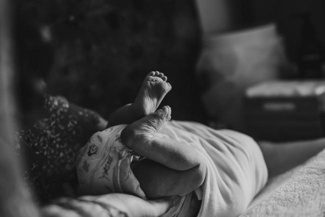 Black and white image of new baby's little feet during lifestyle family photography Perth session