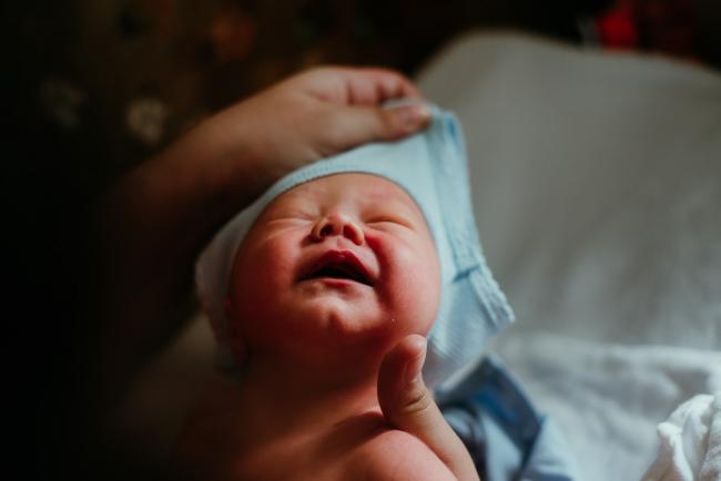 Singlet being pulled over the head of a new baby during lifestyle family photography Perth session