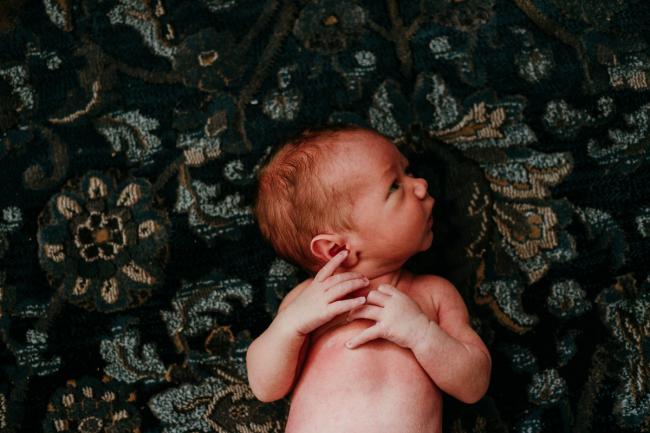 New baby laying on patterned rug during lifestyle family photography Perth session