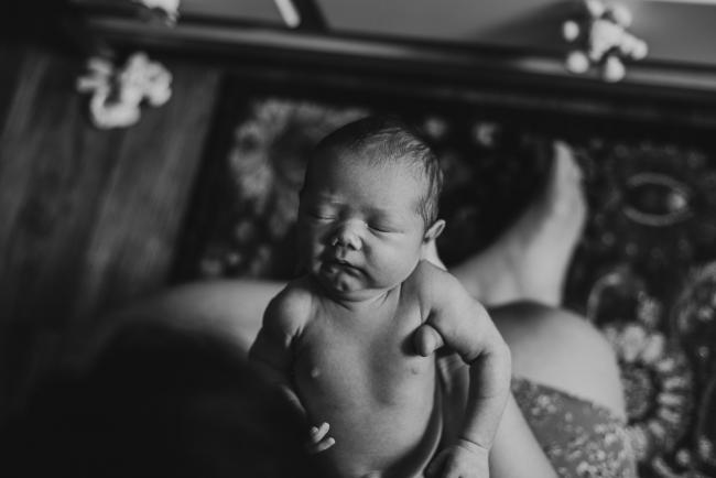 black and white image of new baby being held out in front of mother during lifestyle family photography Perth session