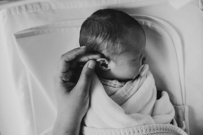 black and white image of mother touching the ear of new baby during lifestyle family photography Perth session