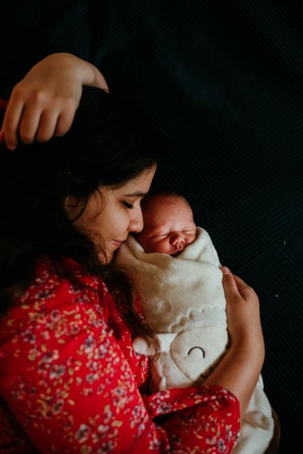 mother laying on bed with new baby during lifestyle family photography Perth session