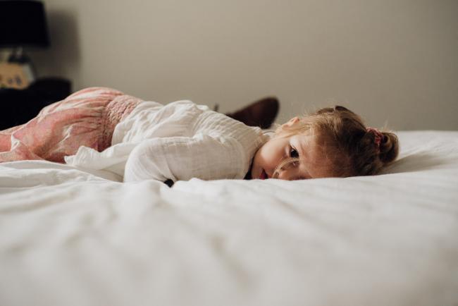 little girl lying on her tummy on the bed during lifestyle newborn photography Perth session