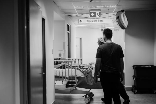 black and white image of mother being wheeled into c-section during Perth birth photography session