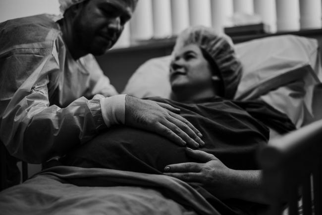 black and white image of father touching his pregnant wife's tummy during Perth birth photography session