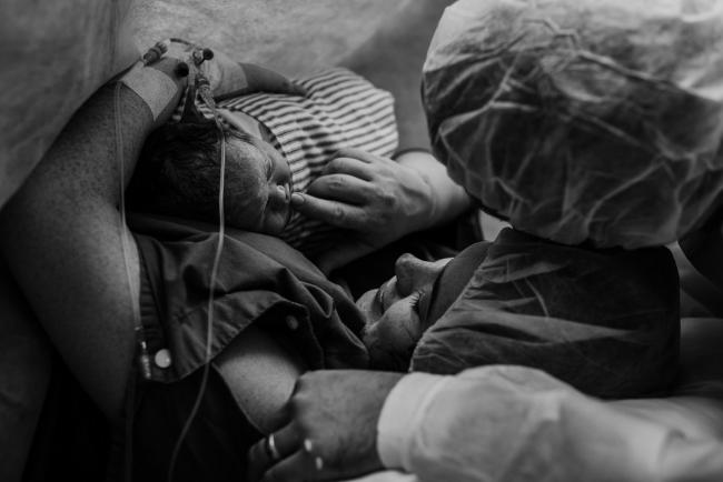 black and white image of mothers first hold with her new baby during Perth birth photography session