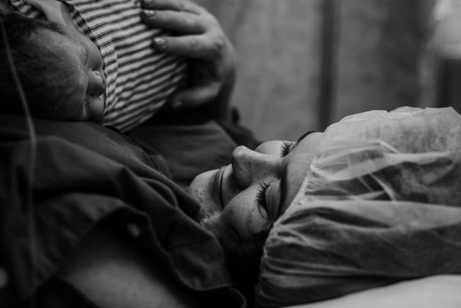 black and white image of mother smiling at her new baby during Perth birth photography session