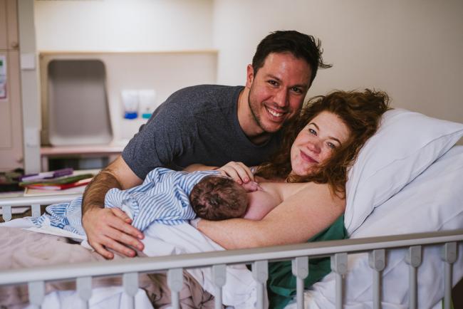 New parents smiling as they hold their new baby during Perth birth photography session