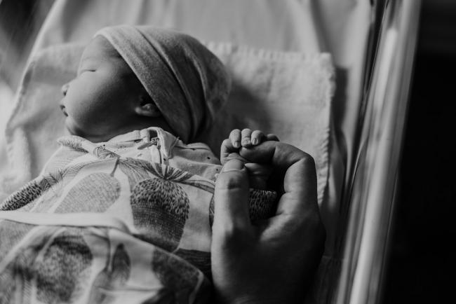 20180809-DSC_6359 black and white image of father holding new baby's hand during Fresh 48 photography Perth session