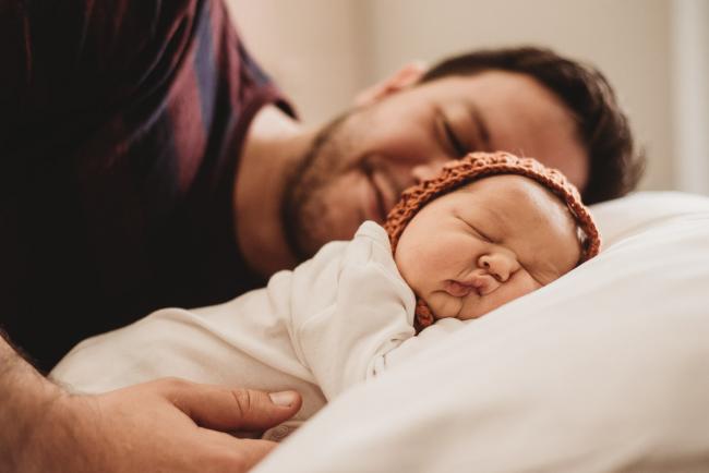 20180809-DSC_7324 father laying behind baby with bonnet on pillow during Fresh 48 photography Perth session
