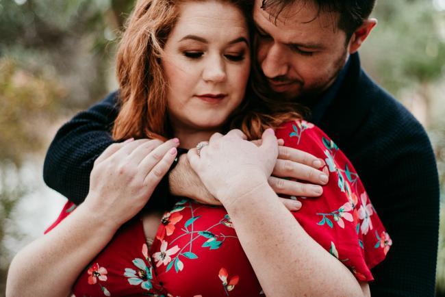 Man wrapping his arms around his partner's shoulders during a maternity session in Perth