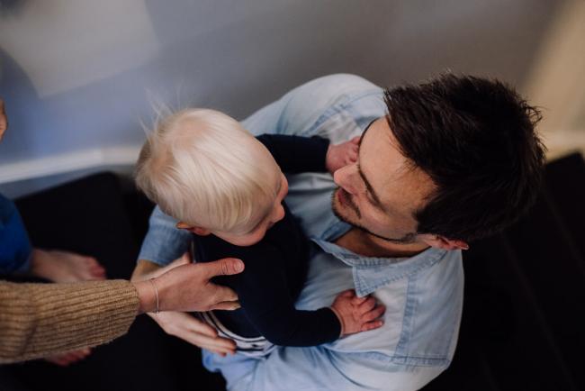 Mother placing their son into his dad's arms during a Perth in-home lifestyle family session