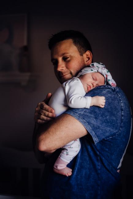 Dad holding his new sleeping baby over his shoulder during a Perth newborn photography session
