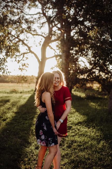 Two sisters laughing and embracing during golden hour at a family session at Perry's Paddock, Perth