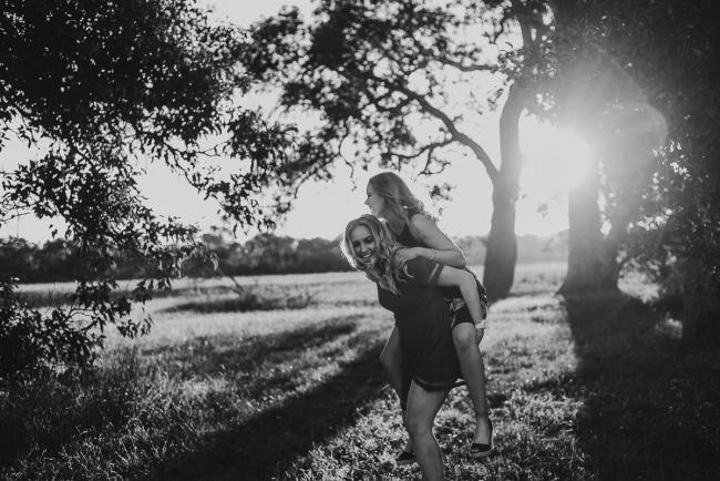 20180909-DSC_5244 black and white image of one sister giving another sister a piggyback ride during golden hour family photography Perth session at Perry's Paddock