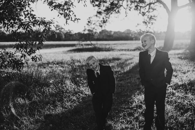 20180909-DSC_5434 Black and white image of two boys standing in suits with their hands in their pockets during golden hour family photography Perth session at Perry's Paddock